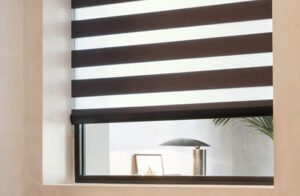 A room textured beige walls features a Double Roller Shade made of Pacifica in Char for a dramatic linear look