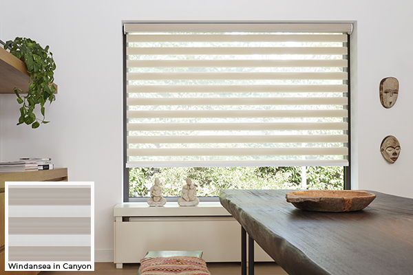 A boho dining room has an unfinished wood table and Double Roller Shades for windows made of Windansea in Canyon