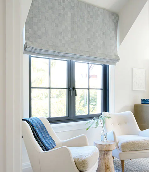 A sitting room features blackout shades for nursery windows made of Flat Roman Shades in Oceana in Slate