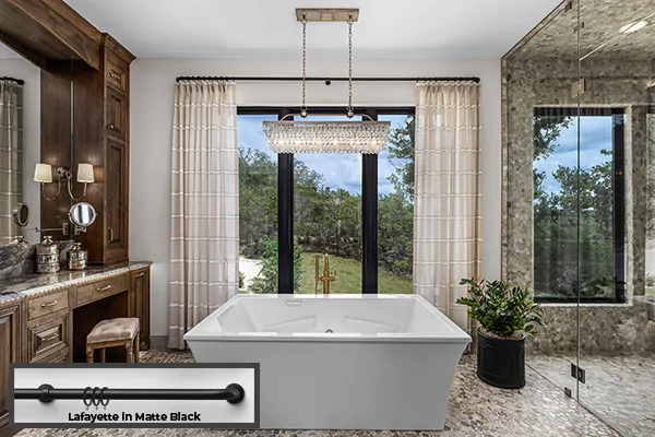 A refined bathroom has French return rods Lafayette in Matte Black with Pinch Pleat Drapery made of Harbor Stripe in Sand