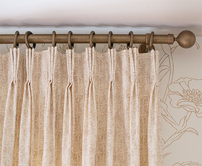 A close up of Pinch Pleat Drapery panels made of Paloma in Sandstone shows the 3-finger pleats pinched 4 inches from the top