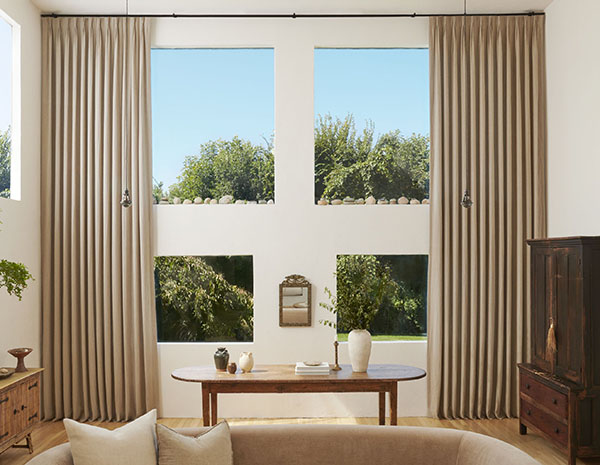 A living room with earthy colors has Pinch Pleat Drapery made of Surrey Stripe in Morel and Natural for added texture