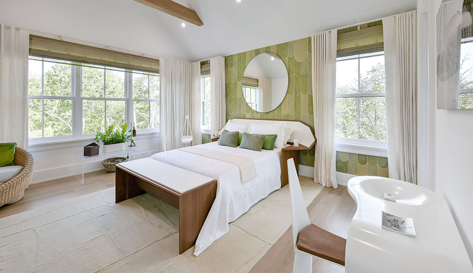 A minimalist bedroom has Ripple Fold Drapery made of Linen Blend in White paired with Woven Wood Shades in Laguna, Tan