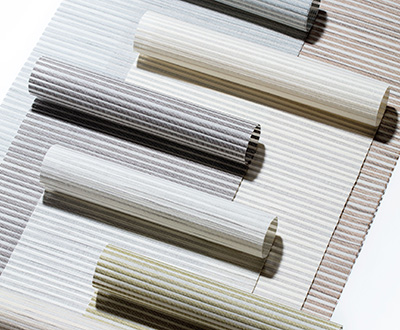 Swatches made of Mesa Verde for Roller Shades for windows overlay each other and are partially rolled for an artistic look