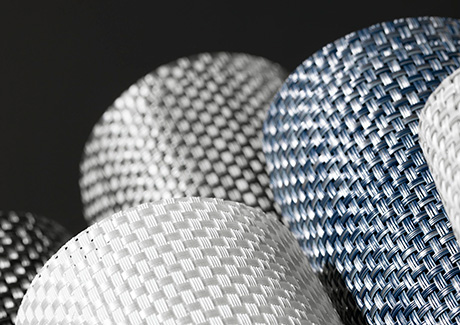 Solar Shade swatches made of Chilewich Basketweave in several colors are neatly rolled up and stacked on one another