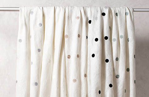 Natural linen fabric with polka dots that can be used for drapery hang decoratively from a laundry line