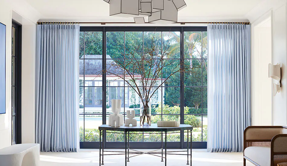 A reception area has tall light blue drapery hung just below the ceiling to show how to hang curtains with crown molding