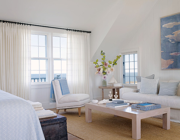 A bright coastal bedroom has neutral curtains made of Victoria Hagan Sankaty Stripe in Moon with a subtle striped design