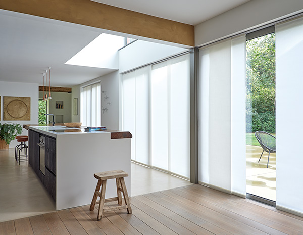 An open kitchen with a large island features sliding glass doors covered with Vertical Blinds made of Park in Winter