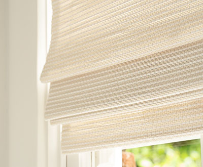 A close up of privacy lined woven shades made of Artisan Weaves Somerset in Cloud shows how some light filters through